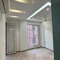 An interior view of a bedroom in the CR Park project, nearing completion. You can see the finished false ceiling with integrated lighting, marble flooring, and newly installed windows, ready for the final touches.