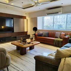 A wide view of a contemporary living room in a Mulund home. We used a mix of leather and fabric sofas, a sleek TV unit, and layered lighting to create a space that's perfect for entertaining.