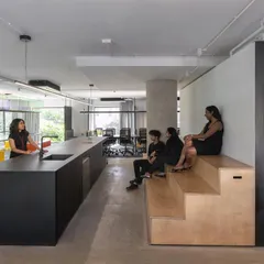 Our new space, Studio 2.0, is designed to foster collaboration, socialization, and focus. This area, with its long kitchen island and tiered wooden seating, serves as the social heart of our studio, a place for informal conversations and shared meals.