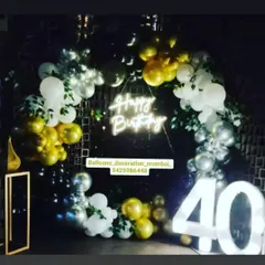 A classic 40th birthday party setup for the night. The decor includes a circular balloon arch in gold, silver, and white, a neon sign, and large marquee numbers.