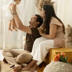 A father lifts his daughter high in the air during their boho-themed studio session, a moment filled with pure joy and laughter.