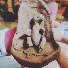 A child holds a clay model of a chick embryo, created as part of their presentation to the class. Making things with their hands helps children process and understand complex biological information.