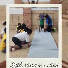 "Little stars in action." A coach assists a young child with a handstand on a mat, providing safe and supportive instruction in foundational gymnastics.