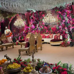 An immersive look into a lavish wedding reception stage, creating a magical floral cave effect. I used thousands of pink and red flowers, complemented by crystal chandeliers and elegant seating to create a truly grand and romantic atmosphere.