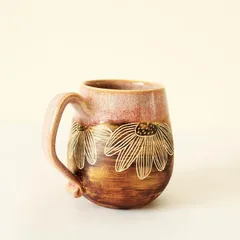 The Pink Sienna mug showcases a beautiful contrast I love to play with. A glossy, rosy pink glaze meets a rustic, earthy finish, with delicate flowers I carve by hand to reveal the clay beneath.