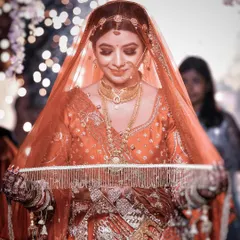 A stunning bridal portrait with a beautiful bokeh background. The bride looks down, holding her veil, in a moment of quiet grace and anticipation before the ceremony begins.