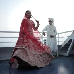 A wedding on a ferry offers endless possibilities for stunning photos. Here, the bride's red lehenga contrasts beautifully with the blue sea and sky, creating a breathtaking image.