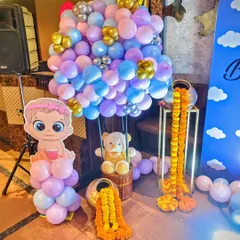 A dreamy baby shower setup combining pastel balloons, a teddy bear in a hot air balloon basket, and traditional marigold garlands for a unique fusion style.