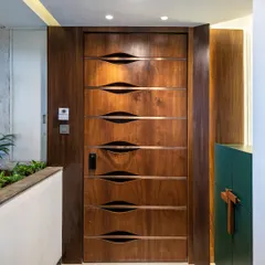 A symphony of style and comfort begins at the door. This custom wooden door at the Filigree House features unique, undulating grooves that create a sense of movement and artistry, offering a hint of the design delights within.