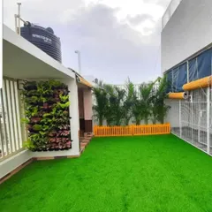 A rooftop garden setup featuring a combination of our services. We installed a vibrant artificial lawn, a compact live vertical garden on the wall, and a row of areca palms for natural screening.