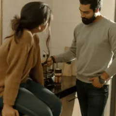 A playful, candid moment during their at-home shoot. He points to something, making her laugh as she sits on the kitchen counter. It’s these unscripted interactions that reveal the true nature of a couple's bond.