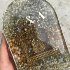 A different view of the arch-shaped keepsake, showing how the silver initials and date complement the golden kaleera inside.