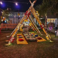 A classic teepee-style gazebo setup on a lawn, decorated with balloons and fairy lights, ready for a memorable outdoor birthday party.