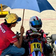 A coach provides one-on-one guidance to a Micro driver on the grid, ensuring he is calm and focused before the race.