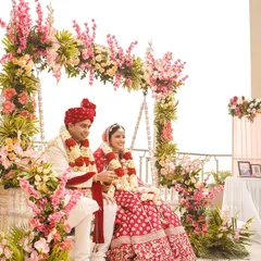 A perfect moment for a rooftop wedding. The couple is framed by a beautiful floral swing, combining blush pink blooms with the open sky for a serene and romantic ceremony.