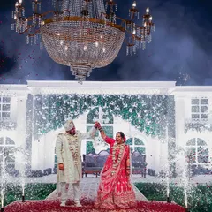 A core memory captured in a single frame. The grand chandelier, the beautiful stage, and the fireworks create a fairytale setting for this couple's varmala, a moment they waited years for.