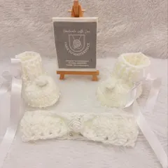 A clear, full view of the handmade crochet booties and headband set, showing the delicate rose and pearl details against the soft white yarn.