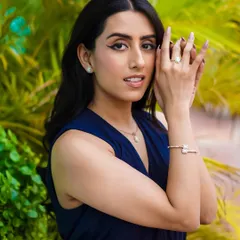 Capturing a moment of connection in this outdoor jewelry shoot. The model's direct gaze and the soft natural light highlight the elegance of the earrings, ring, and bracelet against a vibrant green backdrop.
