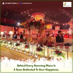A wide view of a grand wedding hall where our team has set up an extensive buffet line, complete with elegant floral arrangements and dedicated staff for each section.