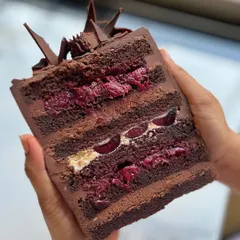 A cross-section of the Modern Black Forest cake I teach in my workshop. You can see the perfect layers of moist chocolate cake, cherry filling, creamy whipped ganache, and luscious whipped dairy cream.
