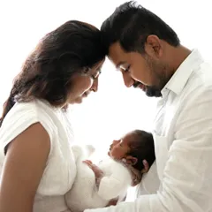 A classic family pose, with mom and dad touching foreheads as they hold their new baby. This is a portrait of pure love and unity.