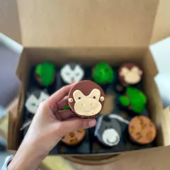 A cute, hand-modelled fondant monkey face on a chocolate cupcake.