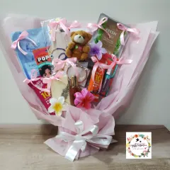 The finished mixed-gift bouquet, beautifully wrapped in pink. This bouquet includes face masks, protein bars, a teddy bear, and perfume, making it a perfect pamper gift.