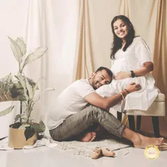A sweet and classic maternity pose, with the partner listening to the baby bump. We use simple props like tiny baby shoes to add a touch of warmth.