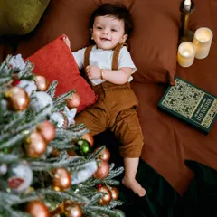 A cozy Christmas scene with a beautifully decorated tree. This little one's happy smile is the best present of all.