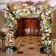 A beautiful floral archway designed for a luxury hotel entrance. We used an abundance of white flowers, dried pampas grass, and gold-painted leaves to create a sophisticated and welcoming structure.