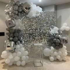 A silver sequin wall provides a fantastic backdrop for photos. Here, I've used an asymmetrical balloon garland in shades of grey, white, and silver, including disco ball foil balloons for extra sparkle.