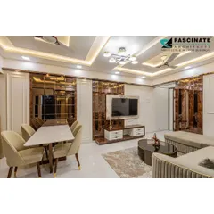 This open-plan living and dining area in Bhiwandi uses reflective bronze mirrors and clean lines to create a sense of spaciousness. The neutral color palette is accented with modern furniture and a stylish chandelier, resulting in a chic and contemporary home.
