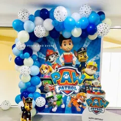 A fun Paw Patrol themed birthday party setup. This decoration features a character-filled backdrop, a blue and white balloon arch with paw print details, and cutouts of the heroic pups.