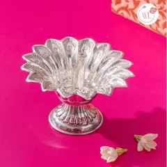 This is a silver-plated peacock diya, with intricate feather details forming the base. It’s a unique and artistic piece that adds a touch of grace and tradition to any wedding gift hamper.