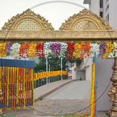 For a traditional wedding, I can create a majestic entrance gate like this one. It features an ornate golden structure decorated with colorful hanging flower arrangements.