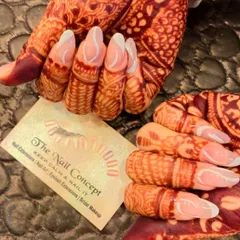 A stunning bridal design created to match the intricate mehendi. These long, almond-shaped nails feature a modern French style with delicate white swirls on the tips.