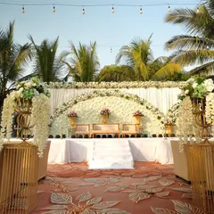 A beautiful and clean stage setup for a daytime ceremony. The semi-circular floral backdrop and cascading wisteria on golden stands create an elegant and sophisticated look.