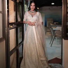 A full-length shot of an elegant white lehenga, perfect for a reception or engagement. The look is accessorized with a simple yet striking diamond necklace set.
