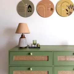 A close-up of a custom-designed console table in sage green. The drawer fronts feature natural rattan inserts and are finished with charming ceramic knobs, showcasing a blend of color, texture, and craft.