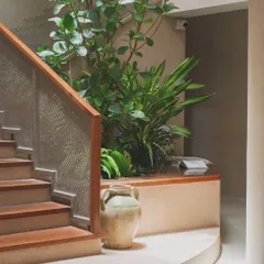A closer look at the staircase atrium garden. The mix of plants with different leaf shapes and heights, including a tall Fiddle-Leaf Fig, creates a lush, layered tropical look.