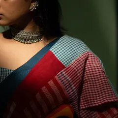 A close-up detail shot of a contemporary saree, showing the mix of checked patterns and bold colors. The oxidized silver choker adds to the modern ethnic vibe.