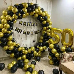 A grand 50th birthday party backdrop. This impressive setup includes a large circular arch made of black and gold chrome balloons, a 'Happy Birthday' banner, and giant gold foil number balloons.