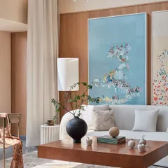 A closer view of the NG Penthouse living area, highlighting the large-scale pastel artwork and the custom burl wood coffee table. These elements add personality and warmth to the minimalist, light-filled space.