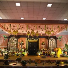 For this naming ceremony, we designed a stage that felt like stepping into a South Indian village home from the 1990s. The setup features a traditional wooden door, intricate pillars, and authentic decor elements like brass vessels and a gramophone.