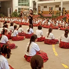 A female instructor addresses a large group of students, creating a safe and relatable learning environment.