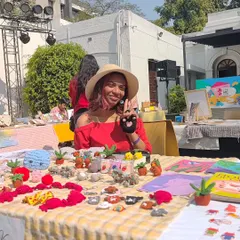 A happy customer posing behind my table, which is covered in tiny crochet friends. Seeing people enjoy my work is the best part of my job.