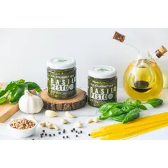 A product shot for The Gourmet Jar's Basil Pesto, styled with its core ingredients like fresh basil, garlic, and pasta. This setup visually communicates the fresh, natural quality of the product.