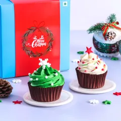 Our Christmas cupcake gift boxes are a perfect festive treat. This set includes a Christmas tree cupcake with green frosting and a classic vanilla cupcake with red and white sprinkles, ready to be gifted.
