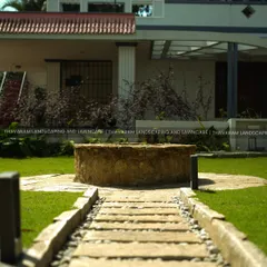 This pathway of stone and pebbles leads the eye toward a rustic stone well, creating a classic, timeless focal point for this residential lawn.