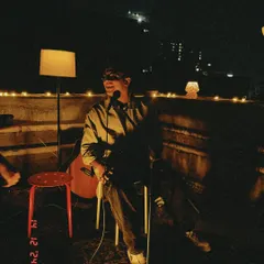 A candid shot from a rooftop song release party. The warm lighting and city skyline in the background created a perfect, relaxed vibe for an acoustic set.